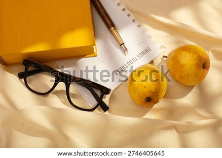 Creative flat lay of fresh pears, planner page, pen and glasses, illuminated by soft natural light