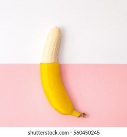 Creative Flat Lay Of A Half Peeled Banana On A Pink And White Background, Top View