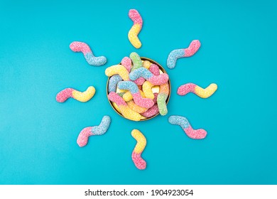 Creative flat lay made of colored sugar coated gummy worms sun shaped around a tin box on a light blue background - Powered by Shutterstock