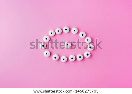 Creative flat lay top view pattern with Halloween googly eyes candy for kids on pastel pink color background with copy space.Trick or Treat, concept for Halloween.Horizontal orientation