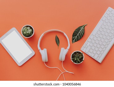 Creative flat lay of workspace desk, office stationery, keyboard, headphones and lifestyle objects on orange background with copy space