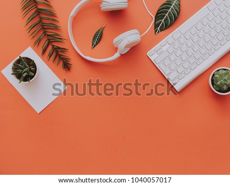 Creative flat lay of workspace desk, office stationery, keyboard, headphones and lifestyle objects on orange background with copy space
