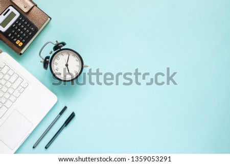 Creative flat lay of workspace desk with laptop,  caculator and notebook on blue colour background.  Business, Insurance or money concept