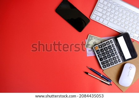 Creative flat lay of workspace desk with laptop, caculator and notebook on red colour background. Business, Insurance or money concept