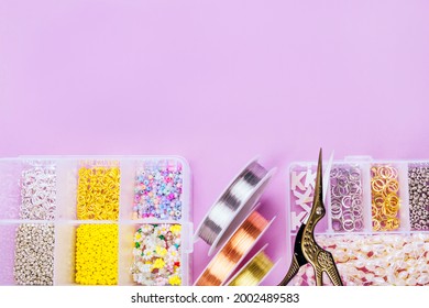 Creative flatlay of different seed and pearl beads with tools for making jewelry, wire string and scissors isolated on pink background.