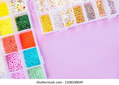 Creative flatlay of different seed and pearl beads in the box on pink background.