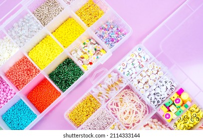 Creative flatlay of different seed and pearl beads in the box on pink background.