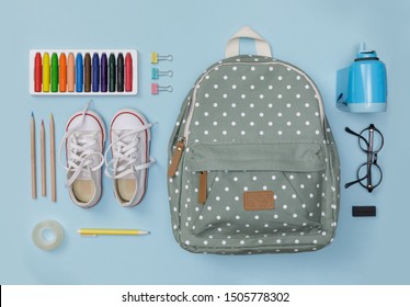 Creative Flatlay Of Education Blue Table With Backpack, Shoes, Colorful Crayon, Eye Glasses, Isolated On Blue Background, Concept Of Education And Back To School