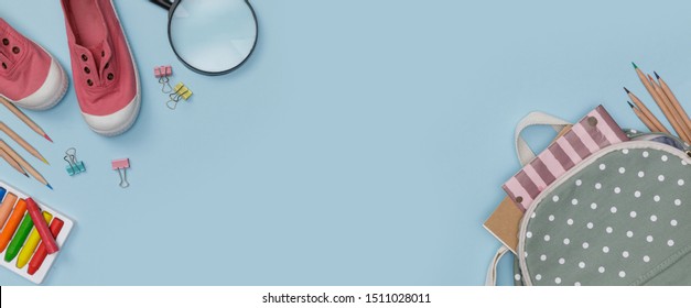 Creative Flatlay Of Education Blue Table With Backpack, Student Books, Shoes, Colorful Crayon, Eye Glasses, Empty Space In Studio Shot Isolated On Blue Long Banner Background,Concept Of Back To School