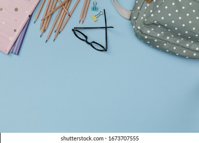 Creative Flatlay Of Education Blue Table With Backpack, Student Books, Shoes, Eye Glasses, Empty Space Isolated On Blue Background, Concept Of Education And Back To School