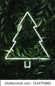 Creative Fluorescent Christmas  Layout Made Of Leaves, Branches And Christmas Tree Neon Sign. Flat Lay. Nature Concept.