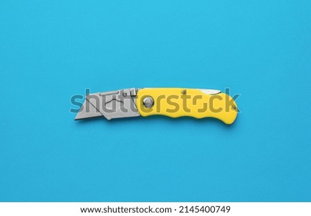 Creative folding knife for cutting on a blue background. Reliable hand tool for cutting. Flat lay.