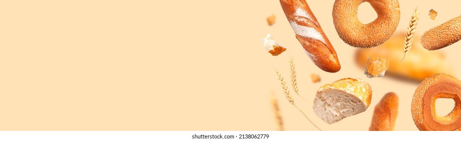 Creative food concept. Various types of bread, ears of wheat flying on beige background. Classic wheat round bread, baguette, bun, sesame bagel. Organic Healthy Fresh bread for bakery advertising