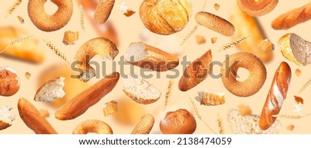 Creative food concept. Various types of bread, ears of wheat flying on beige background. Classic wheat round bread, baguette, bun, sesame bagel. Organic Healthy Fresh bread for bakery advertising