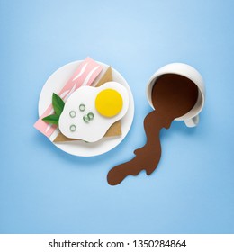 Creative Food Diet Healthy Eating Concept Photo Of Paper Breakfast Fried Egg With Bread Toast Bacon Greens On Plate With Spilled Coffee Cup Mug On Blue Background.