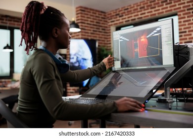 Creative game creator works with graphics for new level design while sitting at desk with two displays. Developing company employee working at computer with two monitors while editing environment.