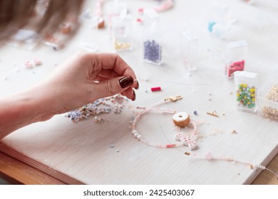 A creative girl is engaged in beadwork. Hobby and small business concept - Powered by Shutterstock