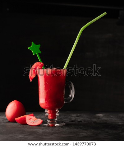 Creative glass in a solid background filled with fresh tomatoes with ice cubes, raw sauerkraut