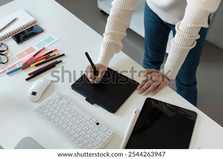 Creative Graphic Designer Working with Digital Tablet and Color Swatches in Modern Office Environment
