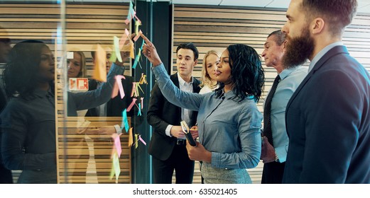 Creative group business people brainstorming putting sticky notes glass wall in office