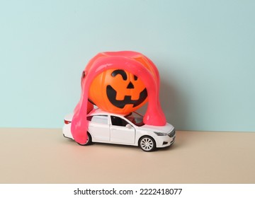 Creative Halloween Layout, Car Model With Neon Slime And Bucket Pumpkin On Two Tone Dark Background. Visual Trend. Trick Or Treat