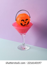 Creative Halloween Layout, Cocktail Glass With Neon Slime And Pumpkin Bucket On Two Tone Pastel Background. Visual Trend. Minimalistic Aesthetic Still Life. Trick Or Treat. Fresh Idea