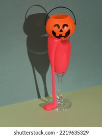 Creative Halloween Layout, Cocktail Glass With Neon Slime And Halloween Bucket On Two Tone Green Background. Visual Trend. Trick Or Treat