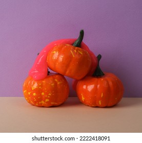 Creative Halloween Layout, Plastic Pumpkins With Neon Slime On Two Tone Pastel Background. Visual Trend. Trick Or Treat