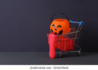 Creative Halloween Layout, Shopping Trolley With Neon Slime And Bucket Pumpkin On Two Tone Dark Background. Visual Trend. Trick Or Treat