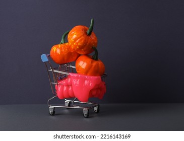 Creative Halloween Layout, Shopping Trolley With Neon Slime And Pumpkins On Two Tone Dark Background. Visual Trend. Trick Or Treat