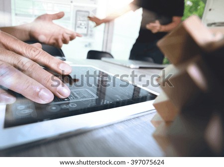 creative hand working digital tablet and wood puzzle with laptop computer and his team as design concept