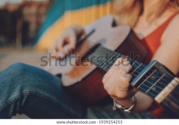 Creative hobbies, guitar lessons, playing musical\
instruments. Acoustic guitars for beginners. Young blonde woman\
with Acoustic guitar\
outdoor