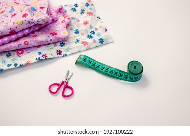 Creative hobby sewing colurful textile scissors and measuringtape sewing centimeter, Top view sewing accessory or tailor equipment, flatlay pink material flower print girly children white background