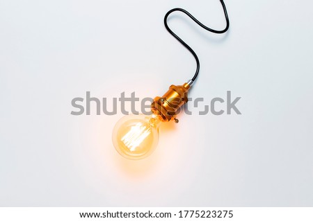 Creative idea concept, designer lamp, modern interior item. Vintage fashionable edison lamp on light gray background. Top view flat lay copy space. Lighting, electricity, background with lamp