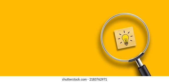 Creative idea concept, magnifying glass and light bulb icon on wooden block with yellow background