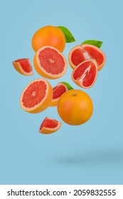 Creative idea with fresh sliced and whole grapefruit floating in the air isolated on blue background. Minimal fruit concept. Vitamins, healthy diet concept. Creative concept with flying fruits.
