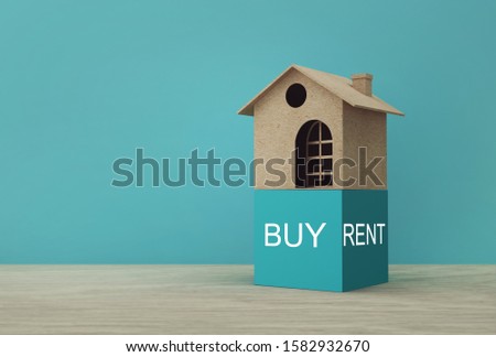 Creative idea of house model paper with Buy or Rent on wooden table. Property investment real estate and house mortgage financial concept.