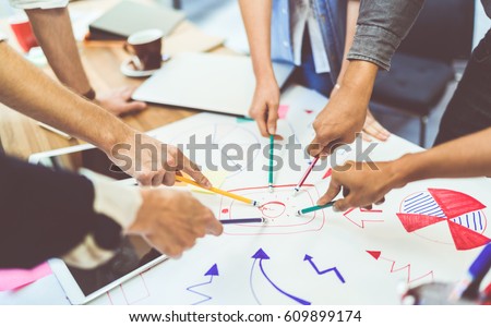 Creative idea teamwork concept. Group of multiethnic diverse team, business partner, or college students in project meeting at modern office. Five people pointing at lightbulb drawings.