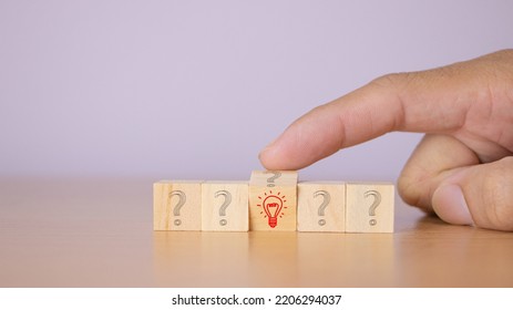 Creative ideas A person's hand flips a lump of wood blocks, patterns, question marks, symbols to light bulb symbols. 