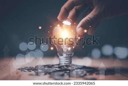 Creative ideas for saving money concept, Businessman holding lightbulb with stack of coins on the table, Planning to manage future financial growth.