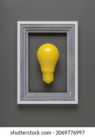 Creative image of a bright yellow light bulb in a gray frame on a gray background. The concept of business ideas.