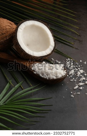 Creative image of half cut coconut and coconut flakes on a dark background