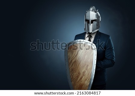 Creative image, a man in a modern suit of a businessman, a knight's helmet on his head, armor. The concept of a modern hero, overcoming difficulties, a crisis, a good manager. magazine style.