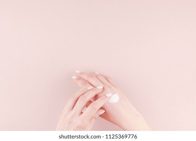 Creative Image Of Woman Moisturizing Her Hand With Cosmetic Cream Lotion With Copy Space On Pink Background In Minimalism Style. Applying Moisturizer To Combat The Dry Skin Cause Frequent Hand Washing