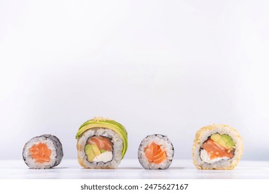 Creative  Japanese seafood sushi set background containing sushi rolls, maki, gunkans with chopsticks on white table