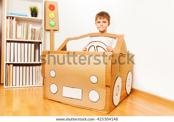 Creative kid boy\
plays with his cardboard\
car