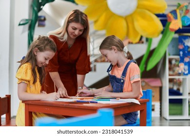 Creative kids during an art class in a daycare center or elementary school classroom drawing with female teacher. - Powered by Shutterstock