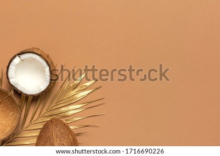 Creative layout with coconuts. Whole and half coconut, golden palm leaf on brown background. Minimal flat lay style, top view copy space. Food concept. Tropical exotic fruit, summer background 