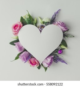 Creative layout with colorful flowers, leaves and heart shape. Anniversary concept.Flat lay.