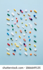 Creative layout of colorful pills and capsules on blue background. Minimal medical concept. Pharmaceutical, Covid-19 or Coronavirus. Flat lay, top view